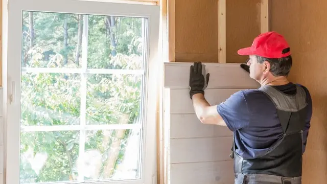 Operario colocando un panel de aislamiento junto a una ventana