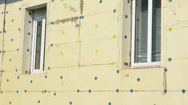 Fachada con paneles aislantes fijados con tacos alrededor de las ventanas